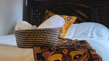 Una cama con una manta estampada, almohadas y una cesta tejida.