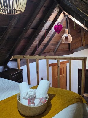 Un dormitorio acogedor en el ático con cama, mesita de noche, cabecero de madera y una lámpara colgante.