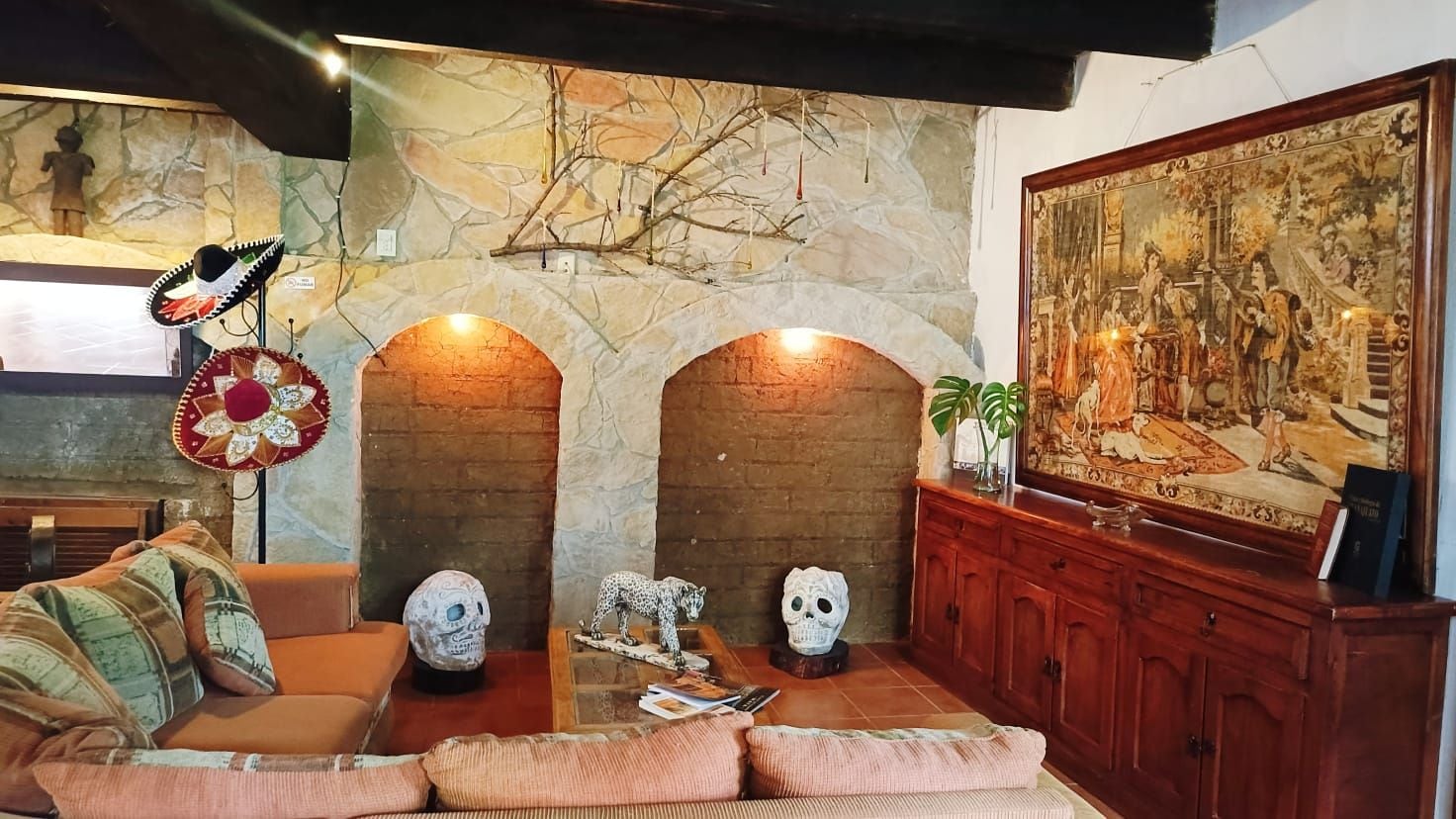 A living room with a stone fireplace, a sofa, a coffee table, and a large painting.