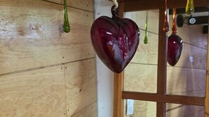 Un intérieur en bois avec une fenêtre et un objet décoratif en forme de cœur suspendu.