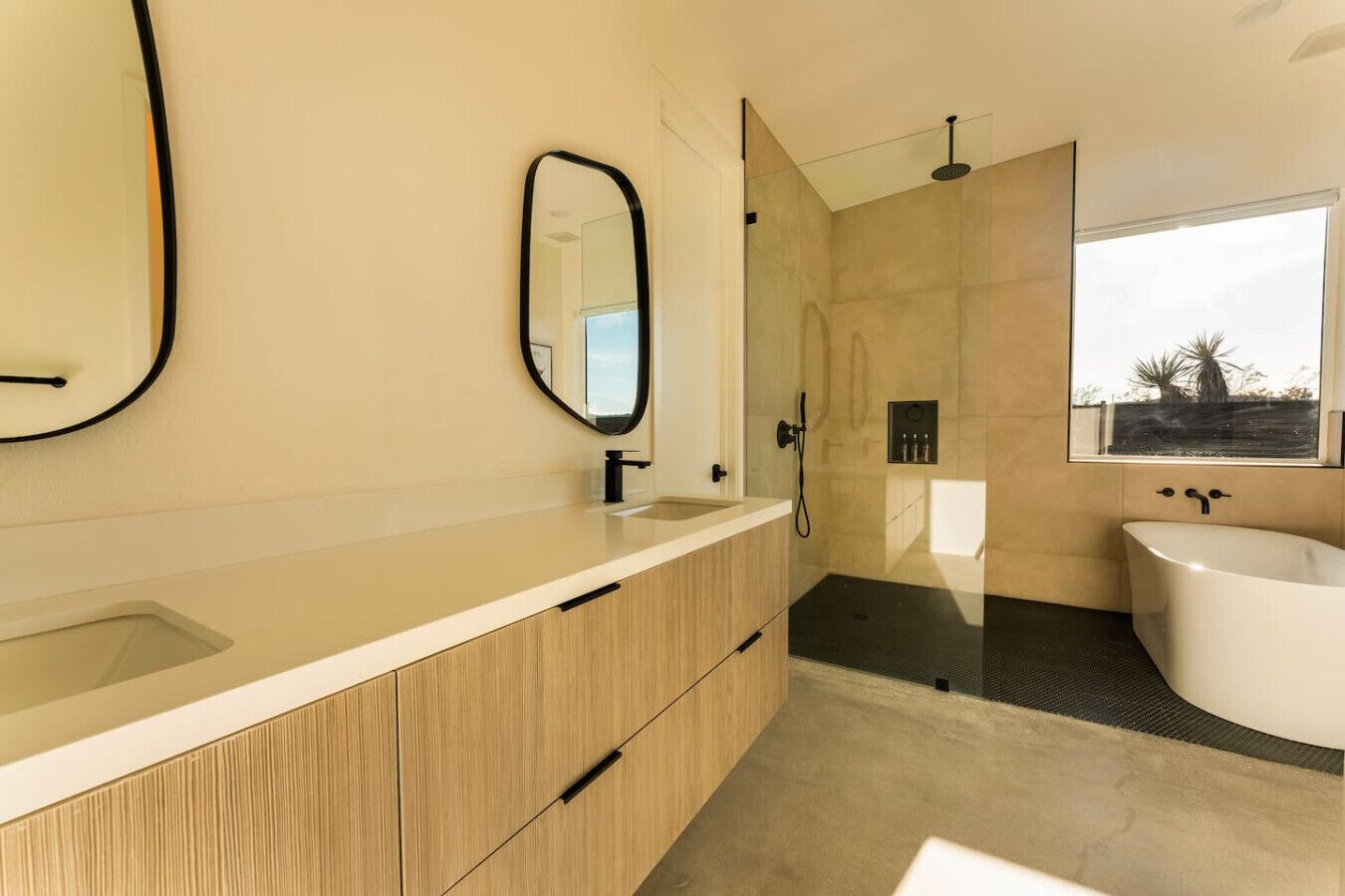 A modern bathroom with a large mirror, a bathtub, and a shower area.