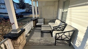 A covered porch with a seating area consisting of a sofa and two chairs, a patterned rug, and a stone planter. - Charming 4-bedroom house in lovely Scranton perfect for families (Scranton)