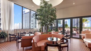 A modern lounge area with a large tree, comfortable seating, and large windows offering city views. - The Crosby Luxury Corner 2BR/2BA Rooftop Pool & GYM | 2801 (Miami)