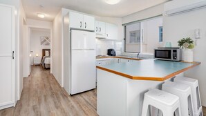 Eine moderne Küche mit weißen Schränken, einer Holz Arbeitsplatte und einer eingebauten Mikrowelle.
