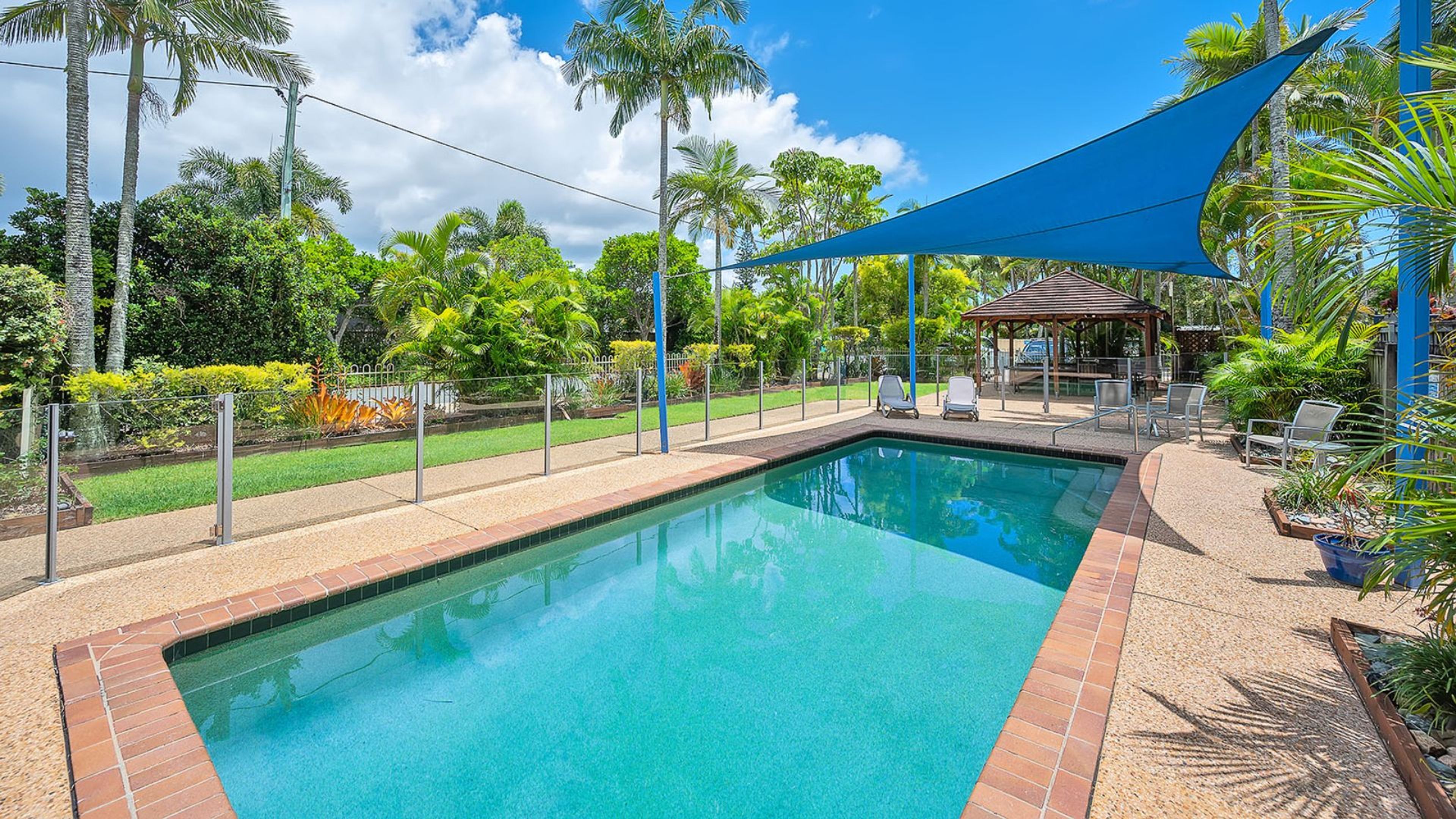 A rectangular swimming pool with clear blue water, surrounded by a brick border.