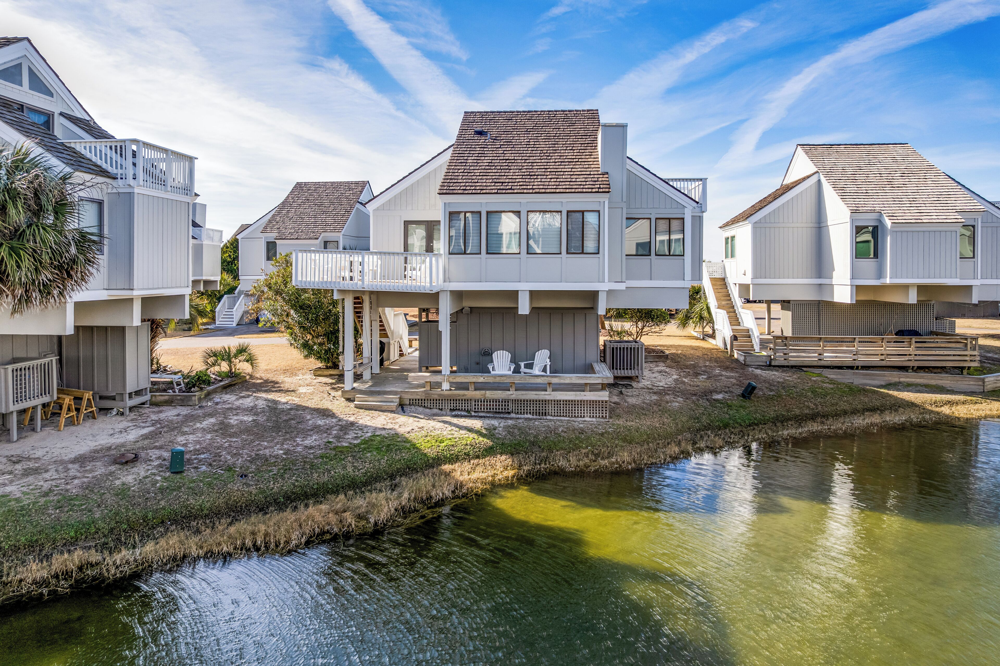 Une zone résidentielle côtière avec des maisons modernes, un petit quai et une étendue d’eau calme.