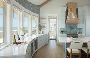 A kitchen with a large window, a stove, and a sink. - After Dune Delight sits on ocean panoramas off BOTH East & South Beaches! (Bald Head Island)