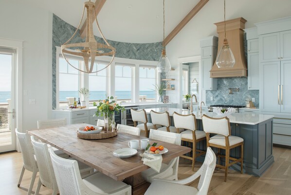 A spacious kitchen with a large island, white cabinetry, and a view of the ocean. - After Dune Delight sits on ocean panoramas off BOTH East & South Beaches! (Bald Head Island)