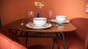 Una mesa de comedor dispuesta con cuencos, platos y cubiertos blancos, junto con un florero con flores.