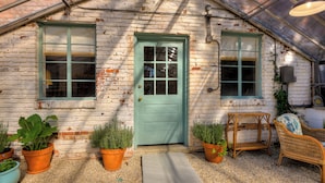 A greenhouse with a green door, potted plants, wicker furniture, and a gravel path. - Beautiful Summerville home located 5 minutes from the Augusta National (Augusta)