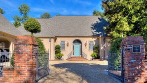 A two-story house with a blue door, brick pillars, and a gravel driveway. - Beautiful Summerville home located 5 minutes from the Augusta National (Augusta)