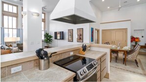 Una cocina moderna con una isla central, horno empotrado y comedor con mesa y sillas de madera.