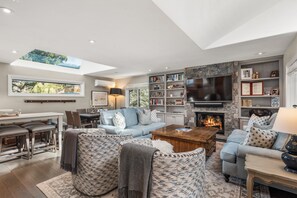 A modern living room with a fireplace, a large TV, and a bookshelf. - Dolomite 10 | 5-Bedroom Townhome | 3 Levels | Walk to Town & Mountain Access (Aspen)