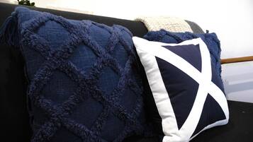A dark blue textured throw blanket and a pillow with a white geometric design on a black sofa.