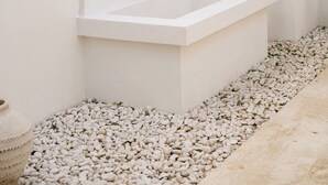 A white outdoor bathtub area with a small tree and pebbles. - Villa Marysol Uluwatu (Uluwatu)