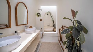 A modern bathroom with a large oval sink, a freestanding bathtub, and a mirror with a wooden frame. - Villa Marysol Uluwatu (Uluwatu)