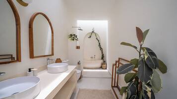 Une salle de bain moderne avec un grand lavabo ovale, une baignoire sur pieds et un miroir encadré en bois.