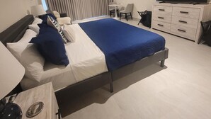 Ett modernt hotellrum med en stor säng, en TV, ett skrivbord och en stol.