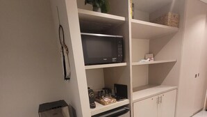 Ett litet, praktiskt pentry med mikrovågsugn, ett litet kylskåp och en kaffemaskin.
