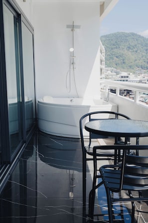 A balcony with a black-tiled floor, a white bathtub, and two black chairs. - 3-Bedroom w/Mountain View at Patong Tower (Tambon Patong)