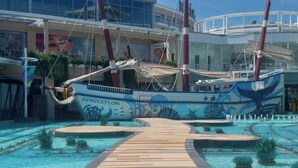 Un área de piscina con una terraza de madera que conduce a una gran piscina, rodeada por dos embarcaciones llamadas 'JUNGCEYLON'.