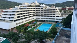 Un hotel de varios pisos con piscina y jardín ajardinado.