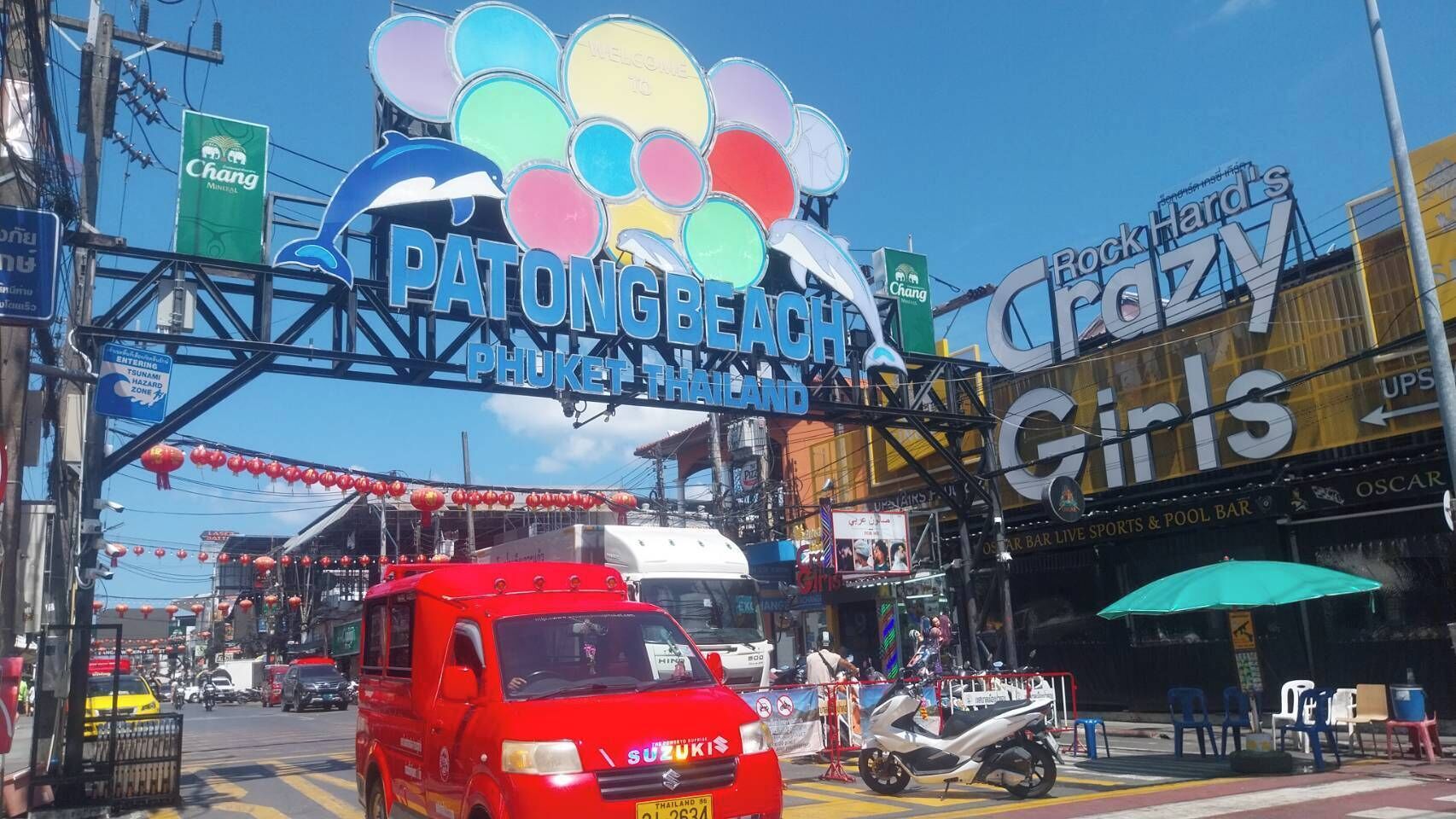 A busy street with a large sign for Patong Beach and Phuket Island.