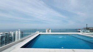 Ein Pool auf dem Dach mit freiem Blick auf das Meer und die umliegenden Gebäude.