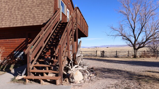 A rustic wooden building with a staircase leading to a window, set against a clear blue sky and a dry landscape. - Peaceful Country Getaway Near Dillon, MT (Dillon)