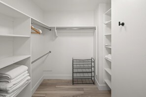 Un dressing avec des murs blancs, un plancher en bois et des étagères métalliques.