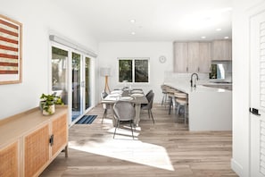 Une cuisine moderne avec des meubles blancs, un îlot central et un coin repas comprenant une table et des chaises.