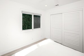 A room with white walls, a window with a view of greenery, and a set of white closets. - Encinitas Getaway | 3-Bedroom Luxury Home | Hot Tub, BBQ | HMS-606 by KBM (Encinitas)
