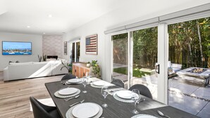 A modern dining area with a table set for six, a sofa, and a TV in the background. - KBM Resorts | 30 Day Rental | 3Bed/2.5 Bath Luxury Home | Hot Tub, BBQ | Encinitas Getaway | HMS-606 (Encinitas)