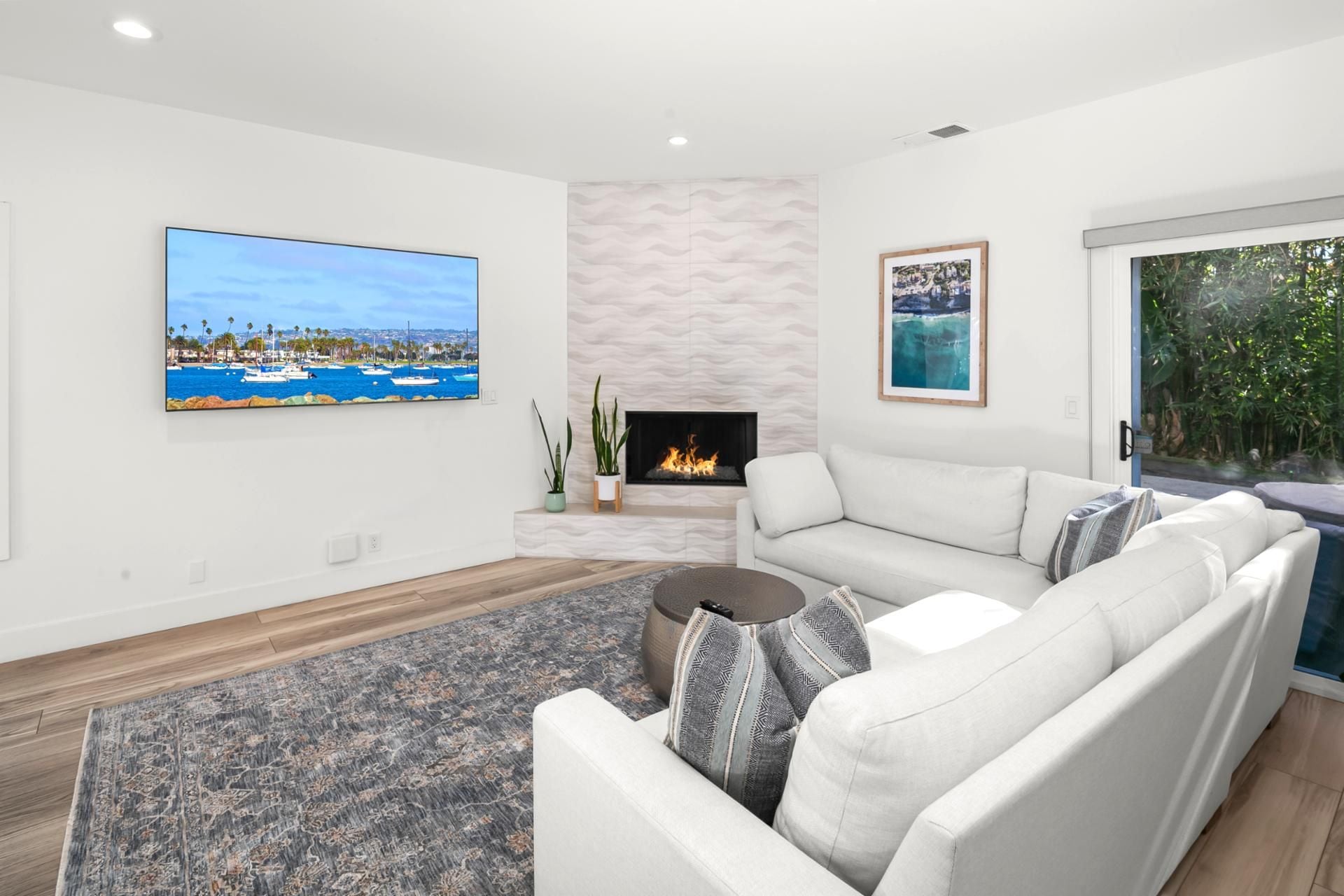 A modern living room with a fireplace, a large TV, and a sofa.
