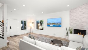 A modern living room with a fireplace, a large flat-screen TV, and a view of the ocean. - KBM Resorts | 30 Day Rental | 3Bed/2.5 Bath Luxury Home | Hot Tub, BBQ | Encinitas Getaway | HMS-606 (Encinitas)