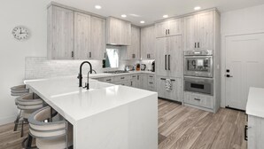 A modern kitchen with a large island, wooden cabinets, stainless steel appliances, and a white tiled backsplash. - KBM Resorts | 30 Day Rental | 3Bed/2.5 Bath Luxury Home | Hot Tub, BBQ | Encinitas Getaway | HMS-606 (Encinitas)