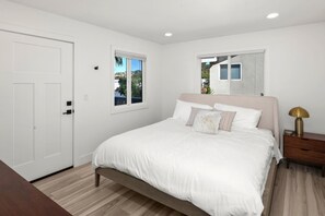 Une chambre à coucher avec un lit, une table de chevet, une lampe et une fenêtre.