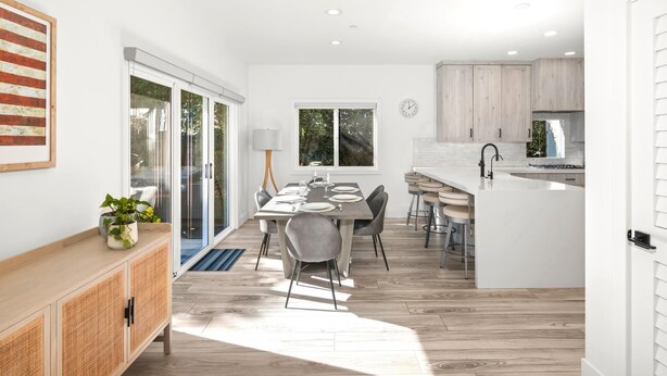 A modern kitchen with white cabinets, a central island, and a dining area with a table and chairs. - KBM Resorts | 30 Day Rental | 3Bed/2.5 Bath Luxury Home | Hot Tub, BBQ | Encinitas Getaway | HMS-606 (Encinitas)