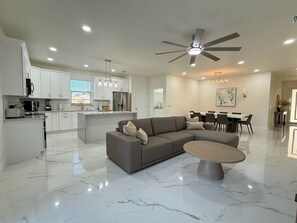 A modern kitchen with white cabinets, a central island, and a dining area with a table and chairs.