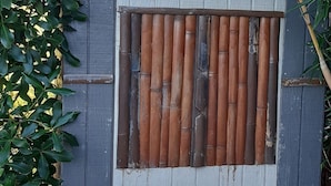 A small, wooden shed with a grey door and a window with bamboo slats. - Cosy caravan in rural setting 5 minutes walk from gorgeous beach (Whitianga)