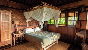 A traditional wooden room with a four-poster bed, a woven mat on the floor, and a window with a view of greenery.