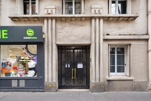 A building facade with a black storefront labeled "SUPRAMARK" and a black wrought iron gate. - Blueground | Saint-Lambert, balcony, nr Eiffel Tower (Paris)