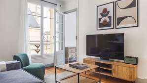 En moderne stue med sofa, sofabord, fjernsyn og kunst på væggen.