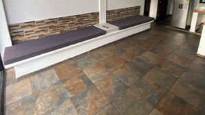 Una stanza con una panchina, una ventola a soffitto e un pavimento piastrellato.
