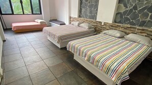 Camera da letto con due letti, una parete decorata in pietra e un'ampia finestra vista verde.