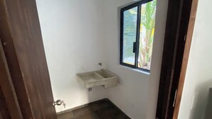 Una stanza piccola e stretta con una finestra, un lavandino e una porta.