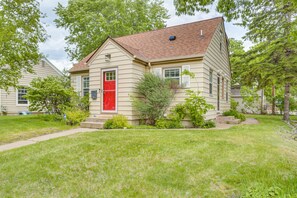 A single-story house with a red door, beige siding, and a sloped roof. - Charming 4BR Home; 3 Levels; Near Airport & MOA (Saint Paul)