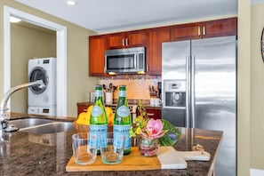 A kitchen with stainless steel appliances, wooden cabinets, a built-in microwave, and a granite countertop. - Honua Kai | Ocean View 4 BR, Sleeps 12 | Car Incl. w/ 6+ Nights | HKK ML-3550 by KBM (Lahaina)