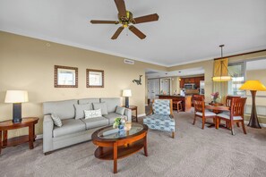 Ein Hotelzimmer mit Sofa, Ohrensessel, Couchtisch, Esstisch, Stühlen, einer Küchenzeile und Deckenventilator.