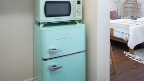 Eine kleine Küchenzeile mit einem Retro-Kühlschrank und einer Mikrowelle, einer Kaffeemaschine und einem Regal mit einer Kaffeekanne.